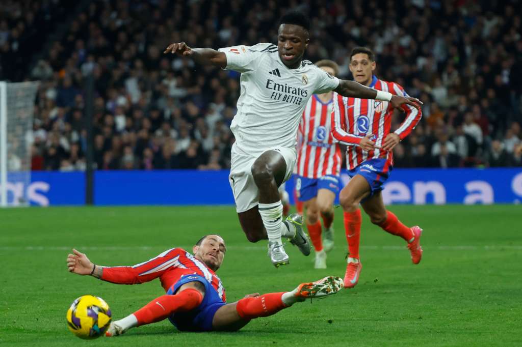 MADRID, 08/02/2025.- El delantero del Real Madrid Vinicius Junior (d) escapa de un defensor del Atlético, durante el partido de LaLiga de fútbol que Real Madrid y Atlético de Madrid disputan este sábado en el estadio Santiago Bernabéu. EFE/Juanjo Martín
