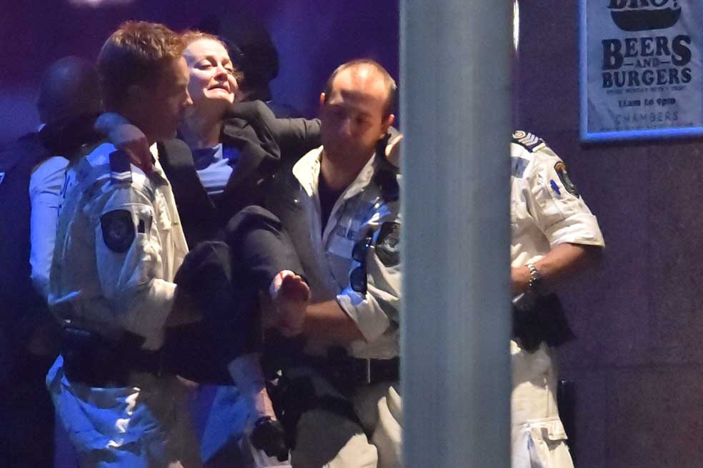 Un policía carga a una mujer tras el asalto al Lindt Chocolat Cafe de Sídney. /AFP