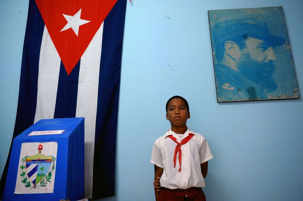 Un niño de un colegio en La Habana junto a uno de los puestos de votación. / AFP