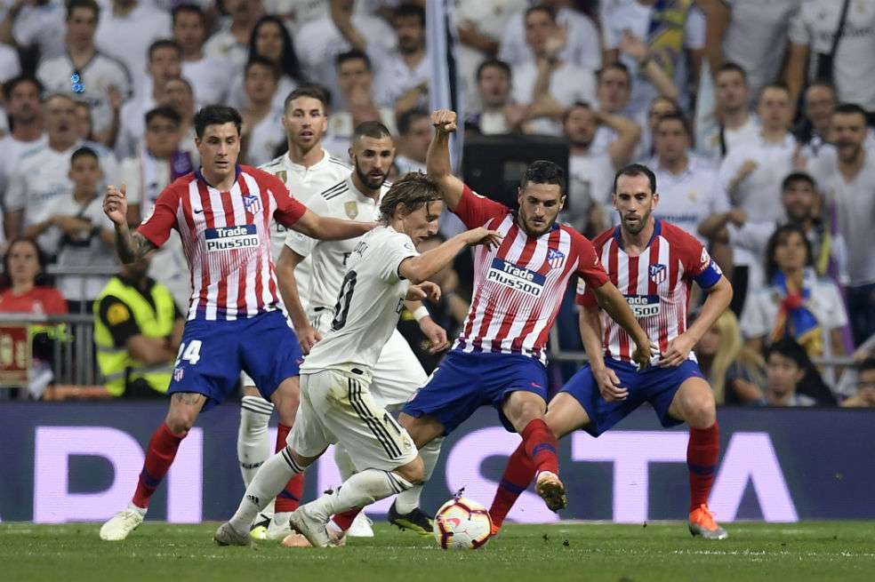 Luka Modric es marcado por Koke durante el encuentro que se disputó en el Santiago Bernabéu. / AFP