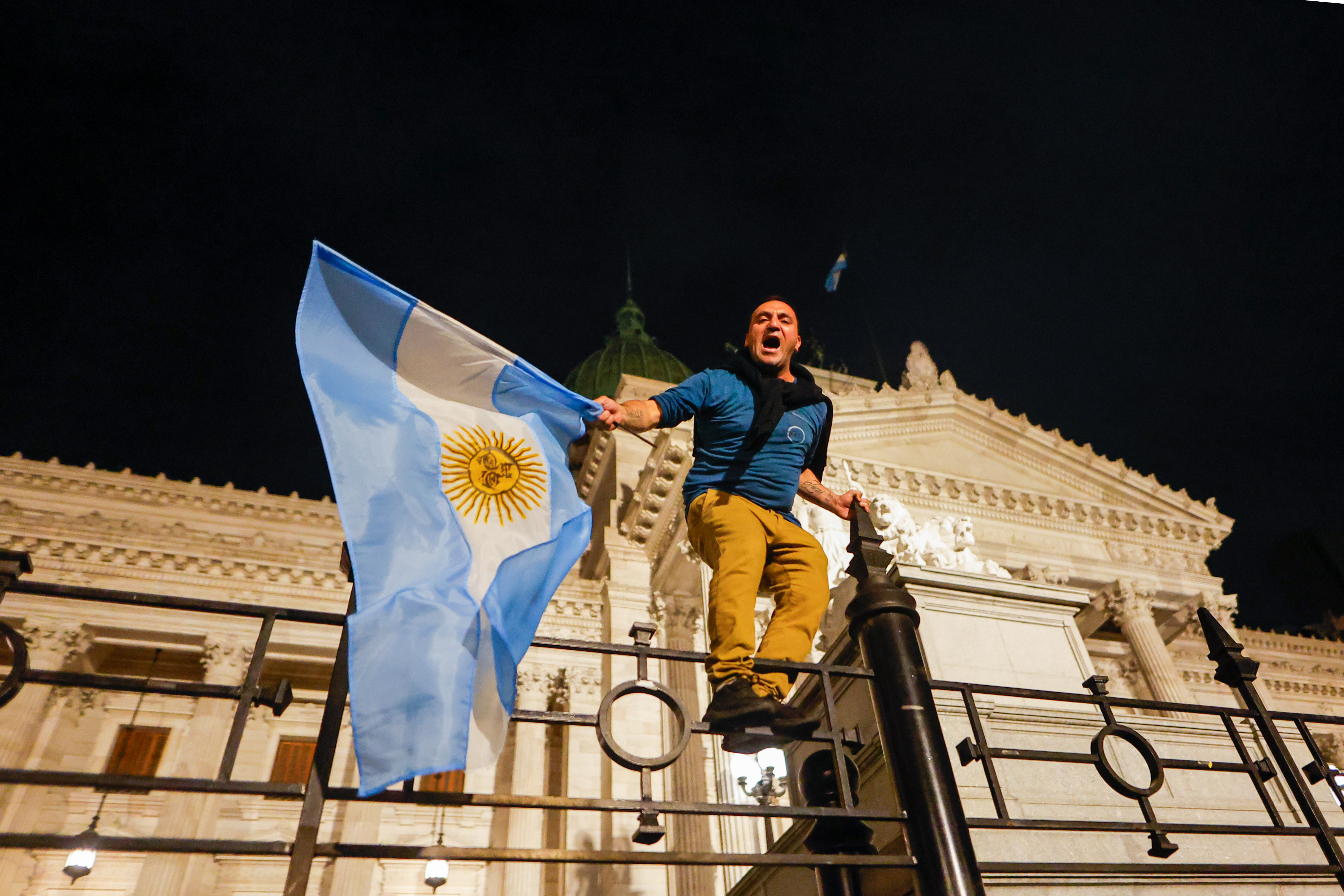 AME5547. CIUDAD DE BUENOS AIRES (ARGENTINA), 20/12/2023.- Un hombre sostiene una bandera argentina y grita arengas como manifestación contra las medidas anunciadas hoy por el presidente Javier Milei, frente al Congreso de la Nación en Buenos Aires (Argentina). Milei anunció la noche de este miércoles un plan que contempla la reforma de más de 300 normas para sentar "las bases de la reconstrucción de la economía argentina". El anuncio del plan de choque del Gobierno se produce el mismo día en que unas 3.000 personas convocadas por organizaciones sociales y de izquierda salieron a las calles de la capital argentina para mostrar su rechazo a la política del presidente ultraliberal. EFE/ Juan Ignacio Roncoroni