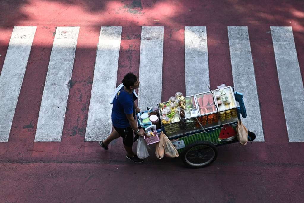 This photo taken on April 30, 2026 shows a street vendor pushing a cart of fresh fruit in Bangkok.