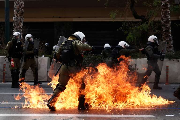 -FOTODELDÍA- ATENAS, 16/03/2023.- Policías antidisturbios intentan en medio del fuego provocado por manifestantes durante unos disturbios tras una manifestación convocada con motivode reciente accidente ferroviario en Grecia, este jueves en Atenas. Sindicatos griegos han convocado un paro de 24 horas en todo el país para pedir responsabilidades a los implicados en la colisión ferroviaria del 28 de febrero. EFE/YANNIS KOLESIDIS