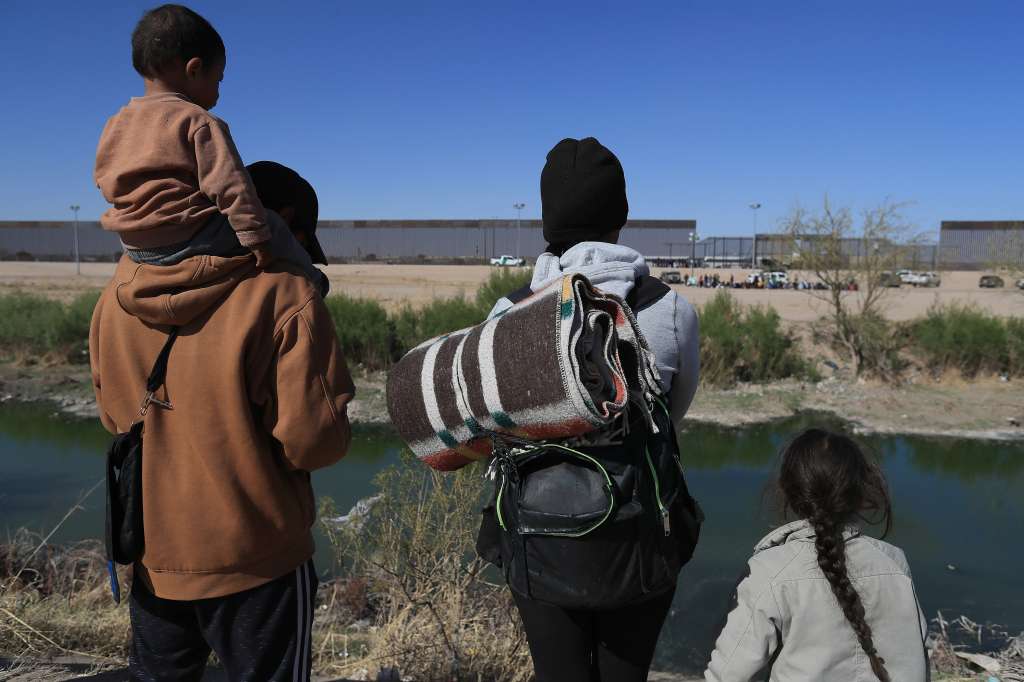 MEX841. CIUDAD JUÁREZ (MÉXICO), 29/03/2023.- Una familia de migrantes a orillas del Río Bravo, observan el muro fronterizo hoy, en Ciudad Juárez, estado de Chihuahua (México). Tras el incendio fatal en un centro migratorio que provocó el fallecimiento de 39 extranjeros en contexto de movilidad el pasado lunes por la noche, cientos migrantes buscaron este miércoles entregarse ante las autoridades de Estados Unidos en la frontera con México. EFE/Luis Torres