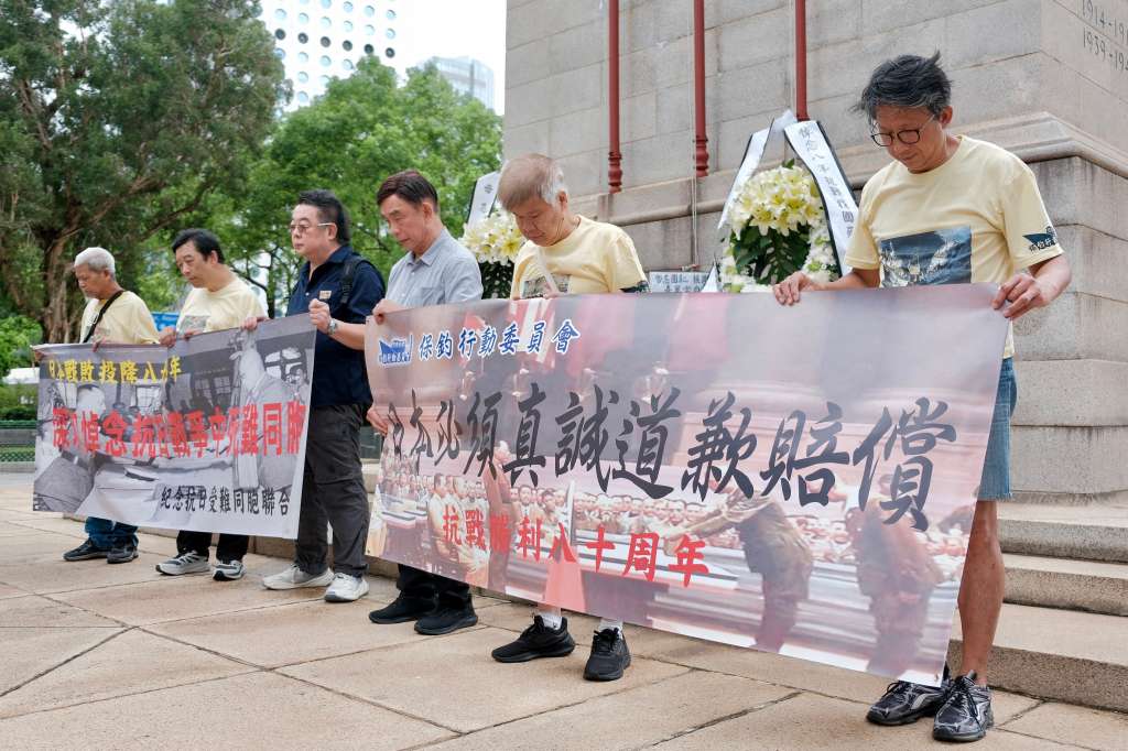 Activists pay silent tribute to the victims of war at The Cenotaph war memorial at the Central district in Hong Kong on August 15, 2025, during a small-scale protest march organised to call on Japan to apologise for its invasion of China during World War II, on the 80th anniversary of Japan's announcement of its surrender.