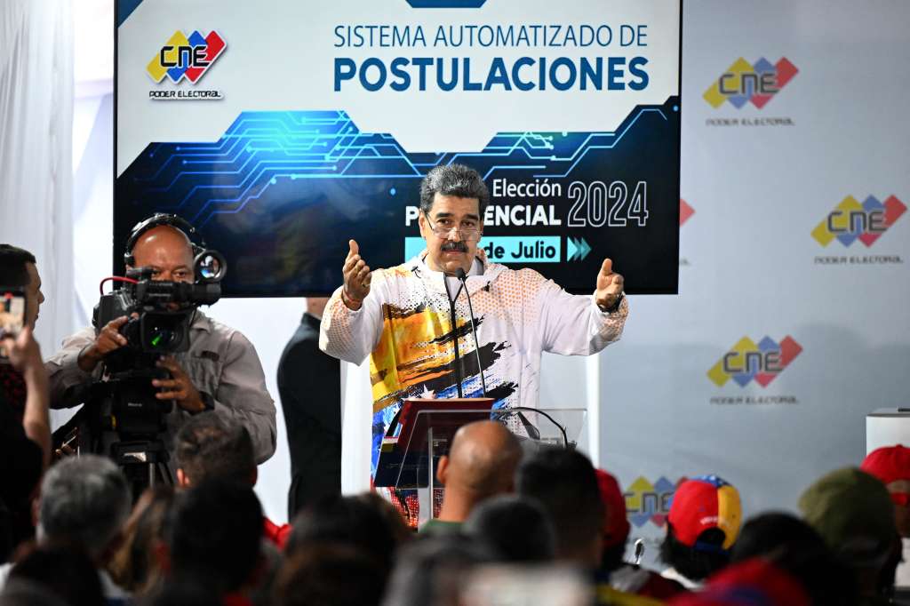 El presidente de Venezuela, Nicolás Maduro, en la sede del Consejo Nacional Electoral (CNE) durante la formalización de su candidatura ante la autoridad electoral venezolana en Caracas el 25 de marzo de 2024. El presidente Nicolás Maduro registró oficialmente el lunes su candidatura en las elecciones de julio, mientras que la oposición quedó bloqueada para inscribir a su aspirante a falta de pocas horas para que se agote el tiempo. Maduro, de 61 años, formalizó su candidatura a la presidencia para un tercer mandato con gran fanfarria, mientras miles de personas acudían a manifestarse detrás de él y del gobernante Partido Socialista Unido de Venezuela.
