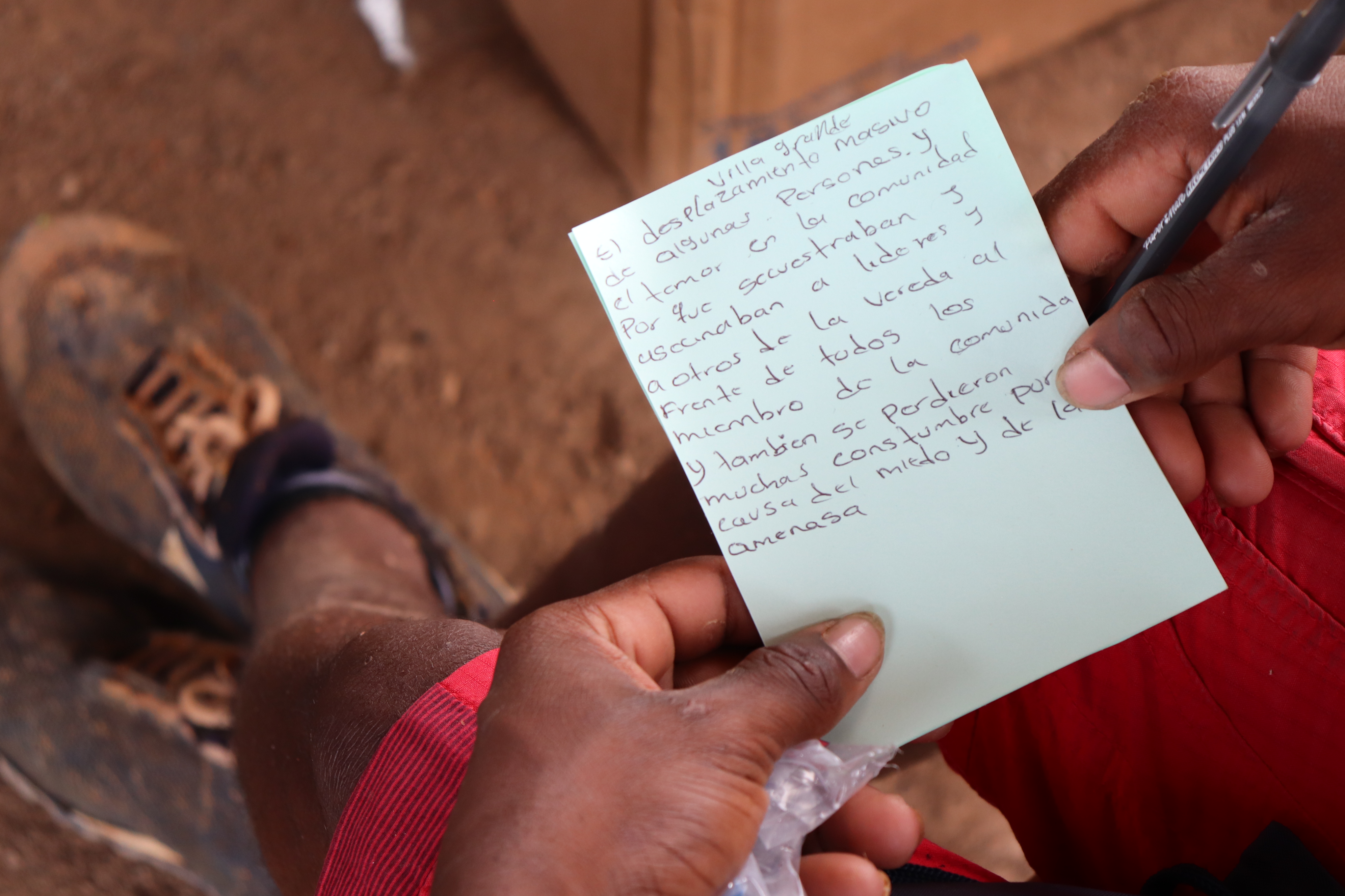 Manos de un hombre afro que sostienen un papel en el que escribió sobre los asesinatos de líderes.
