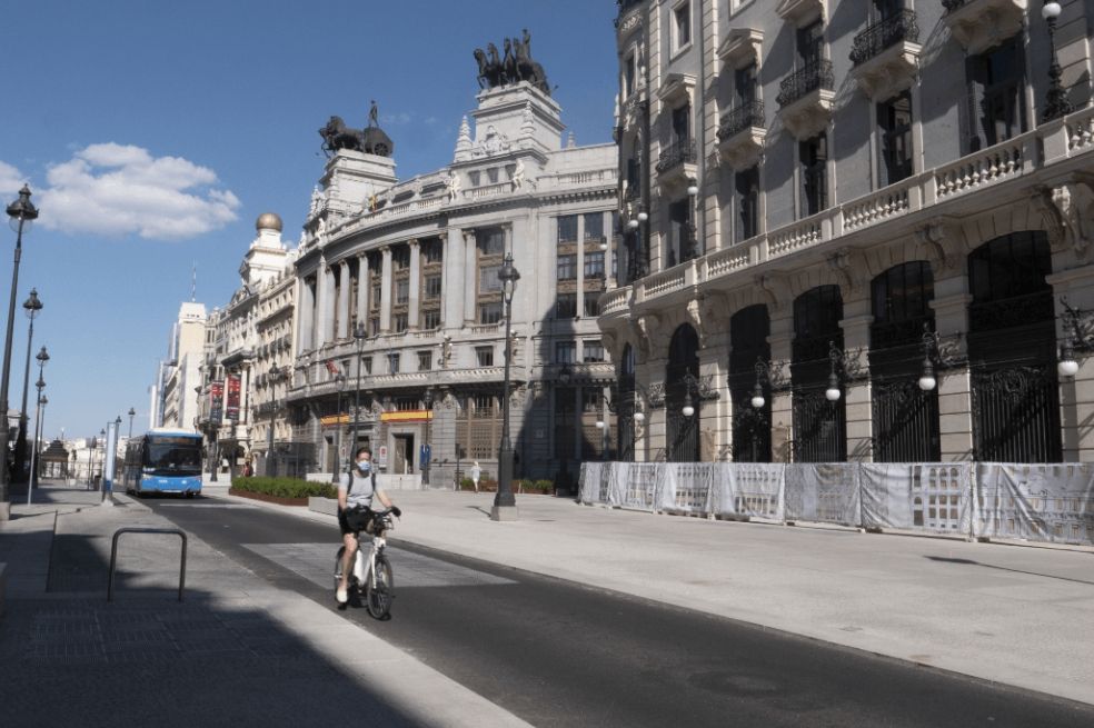 Un hombre pasea en bicicleta con mascarilla por Madrid.