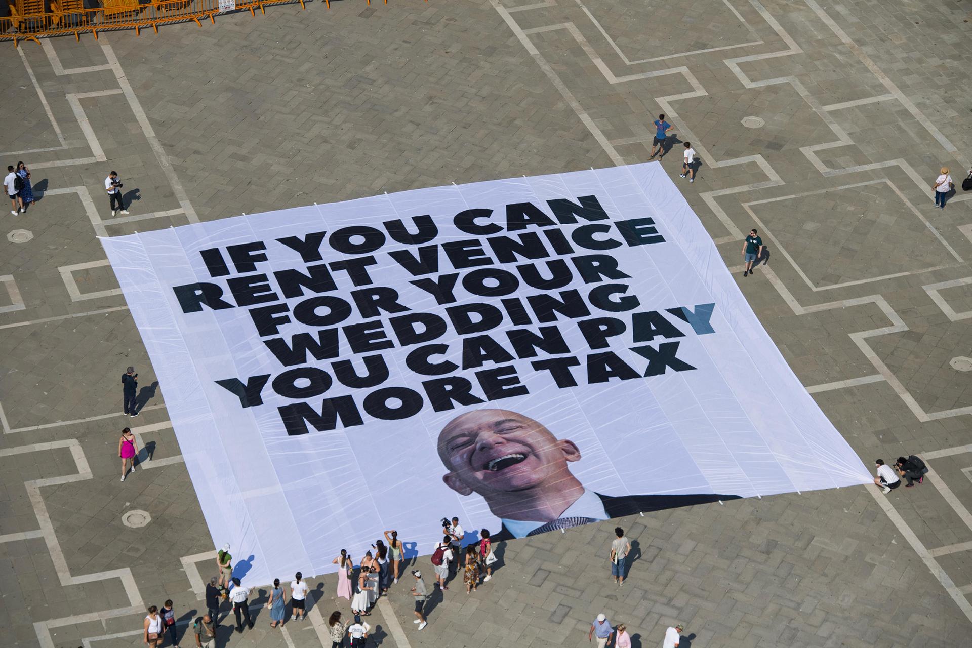 VENICE (Italy), 23/06/2025.- A handout photo made available by Greenpeace press office shows activists of the environmental group Greenpeace unfolding a giant banner with the image of US businessman and Amazon founder Jeff Bezos, and a slogan reading 'If you can rent Venice for your wedding you can pay more tax' at St Mark's Square in Venice, Italy, 23 June 2025. Venice will host the wedding of Jeff Bezos and his fiancee journalist Lauren Sanchez in June 2025. (Protestas, Italia, Venecia) EFE/EPA/GREENPEACE PRESS OFFICE HANDOUT HANDOUT EDITORIAL USE ONLY/NO SALES
