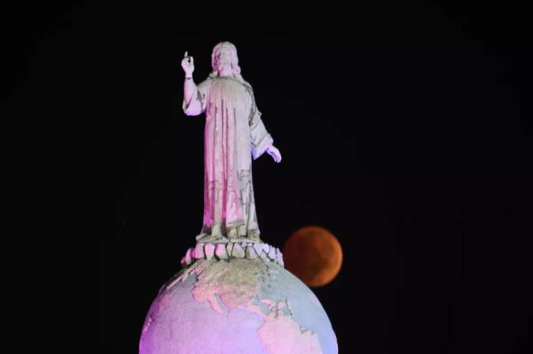 La luna del Castor completamente eclipsada pasa detrás del Monumento al Divino Salvador del Mundo en San Salvador, El Salvador.