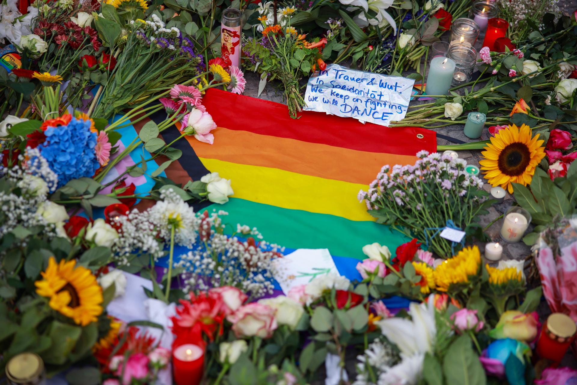 Berlin (Germany), 26/07/2026.- Flowers lie around a rainbow flag during a mourning in front of the Brandenburg Gate near the scene where a vehicle plowed into a crowd on the sideline of the Christopher Street Day (CSD) parade in Berlin, Germany, 26 July 2026. German Minister of Interior Dobrindt has said the vehicle ramming, which killed one person and injured 29 others on 25 July, is being investigated as a terror attack. (Alemania) EFE/EPA/CLEMENS BILAN