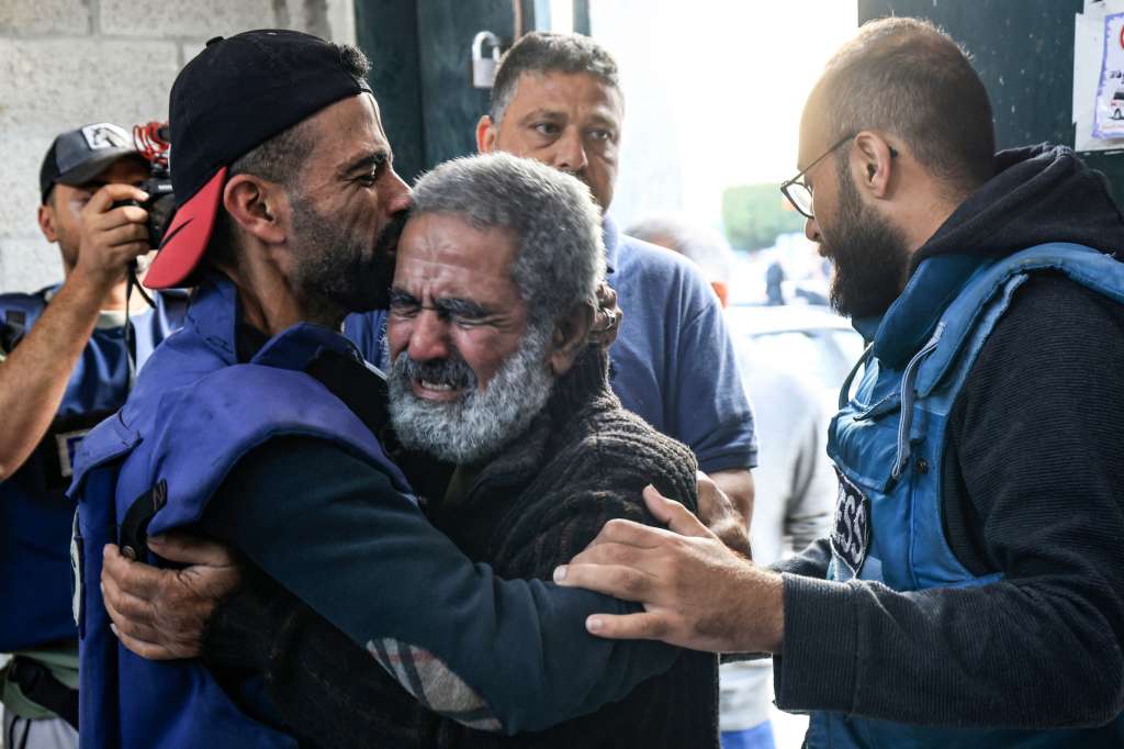 El camarógrafo palestino Mohammed Alaloul (izq.) abraza a su padre después de que dos de sus hijos y su hermano murieran en un ataque israelí contra el campo de refugiados de Al-Maghazi en Deir Balah, en el centro de la Franja de Gaza, frente al hospital de Al-Quds en el mismo ciudad el 5 de noviembre de 2023.