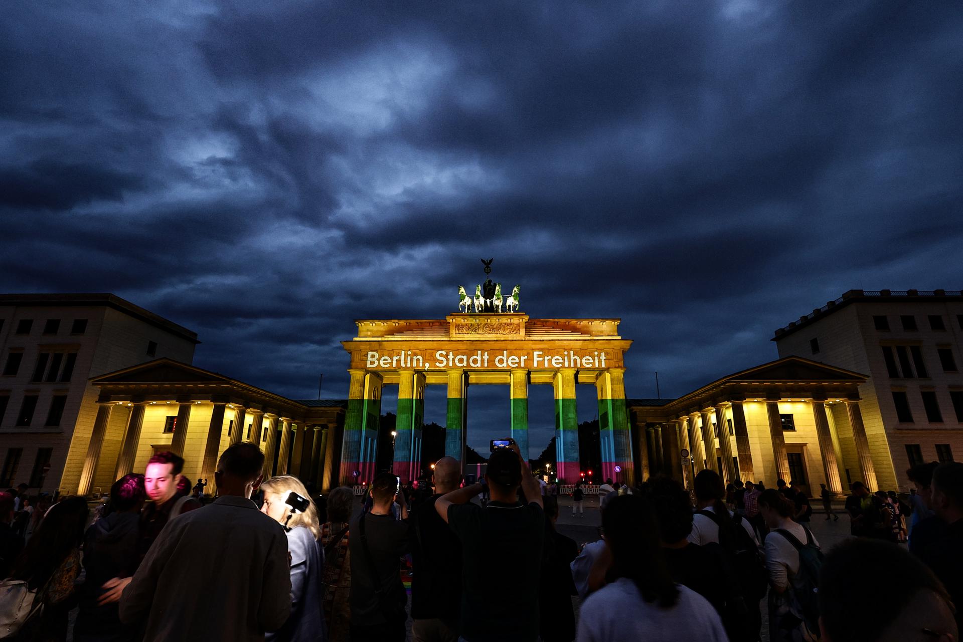 BERLIN (Germany), 26/07/2026.- People mourn in front of the Brandenburg Gate, illuminated with the message “Berlin, city of freedom,” near the scene where a vehicle was driven into a crowd beside the Christopher Street Day (CSD) parade route in Berlin, Germany, 26 July 2026. German Interior Minister Alexander Dobrindt said the 25 July vehicle ramming, which killed one person and injured 29 others, is being investigated as a terrorist attack. (Terrorista, Atentado terrorista, Alemania) EFE/EPA/FILIP SINGER