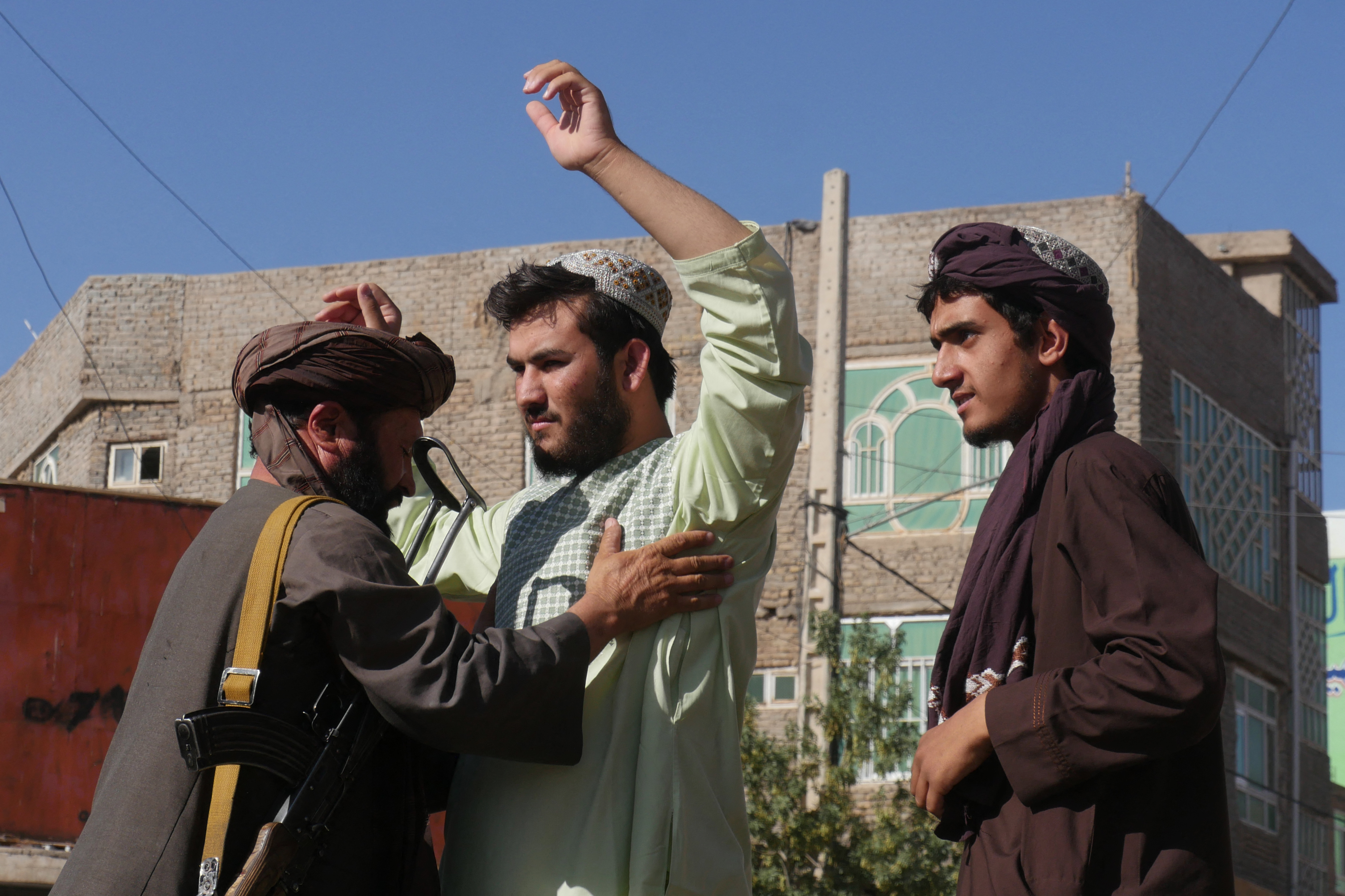 Un combatiente talibán (izquierda) cachea a los hombres en un puesto de control después de una explosión durante la oración del viernes en la mezquita de Gazargah, en Herat, el 2 de septiembre de 2022. -