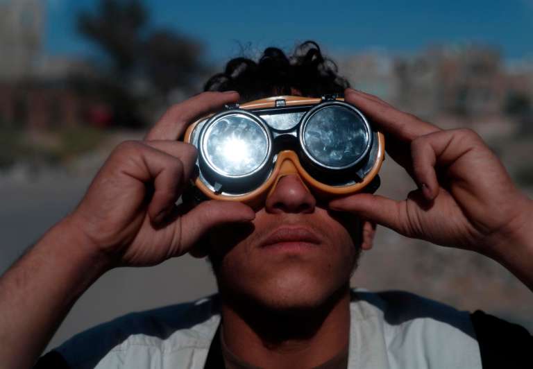 Un hombre lleva unas gafas protectoras para observar un eclipse solar parcial en Sana'a, Yemen.
