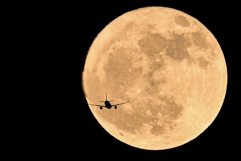 Un avión pasa por delante de la luna llena, conocida como «Luna de fresa», en Chongqing, suroeste de China, el 11 de junio de 2025.