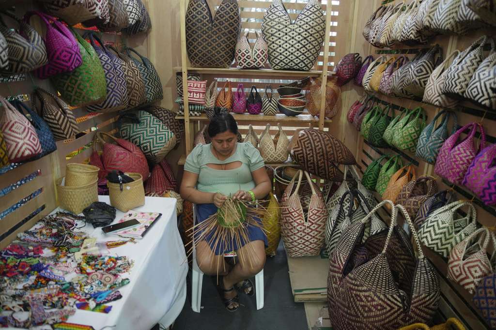 AME9939. CALI (COLOMBIA), 13/08/2025.- Una mujer teje un bolso artesanal en el Festival de Música del Pacífico Petronio Álvarez este miércoles, en Cali (Colombia). El Petronio Álvarez en su XXIX versión, que se celebra del 13 al 17 de agosto, es el evento de cultura afro más grande de Latinoamérica. EFE/ Ernesto Guzmán