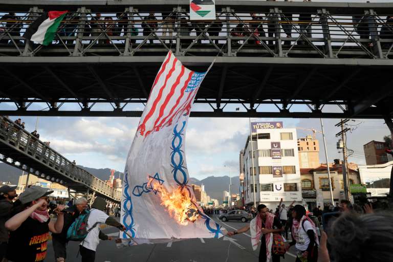 AME5688. BOGOTÁ (COLOMBIA), 07/10/2025.- Personas prenden fuego a una bandera durante una manifestación en apoyo a Palestina con motivo del segundo aniversario del ataque de Hamás contra Israel, este martes en Bogotá (Colombia). EFE/ Carlos Ortega