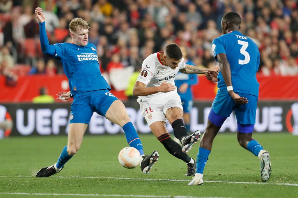 SEVILLA, 16/02/2023.- El centrocampista argentino del Sevilla Erik Lamela (c) disputa el balón con Jordan Teze (d), defensa neerlandés del PSV Eindhoven durante el encuentro de ida de la ronda preliminar de UEFA Liga Europa que Sevilla FC y disputan este jueves en el estadio Sánchez-Pizjuán, en Sevilla. EFE/José Manuel Vidal
