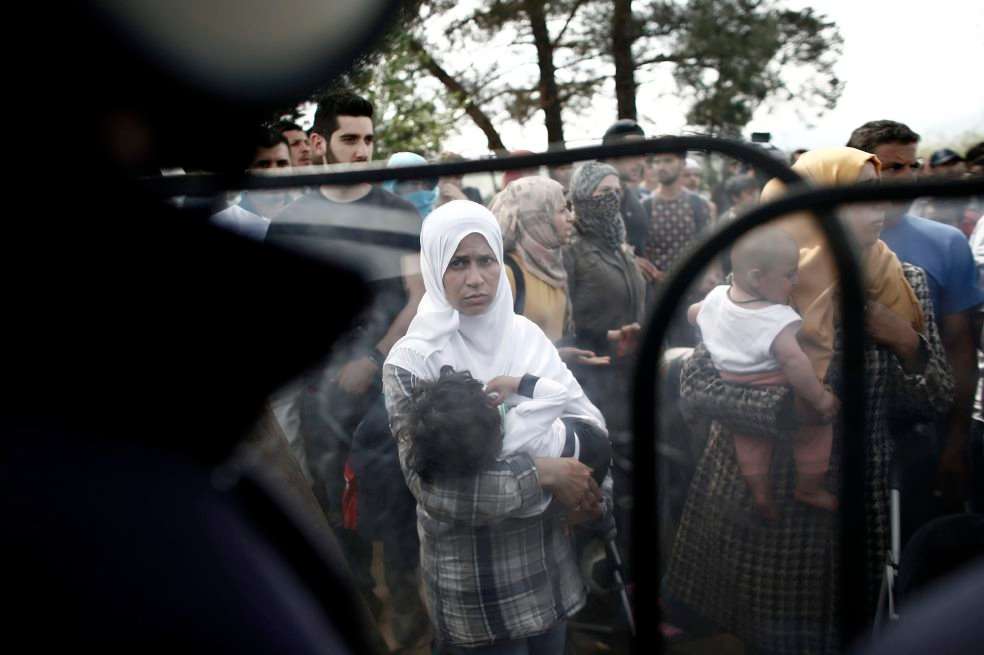 Una mujer con su hijo observa a los policías durante una manifestación que pide a Grecia la apertura de las fronteras a Macedonia. / EFE