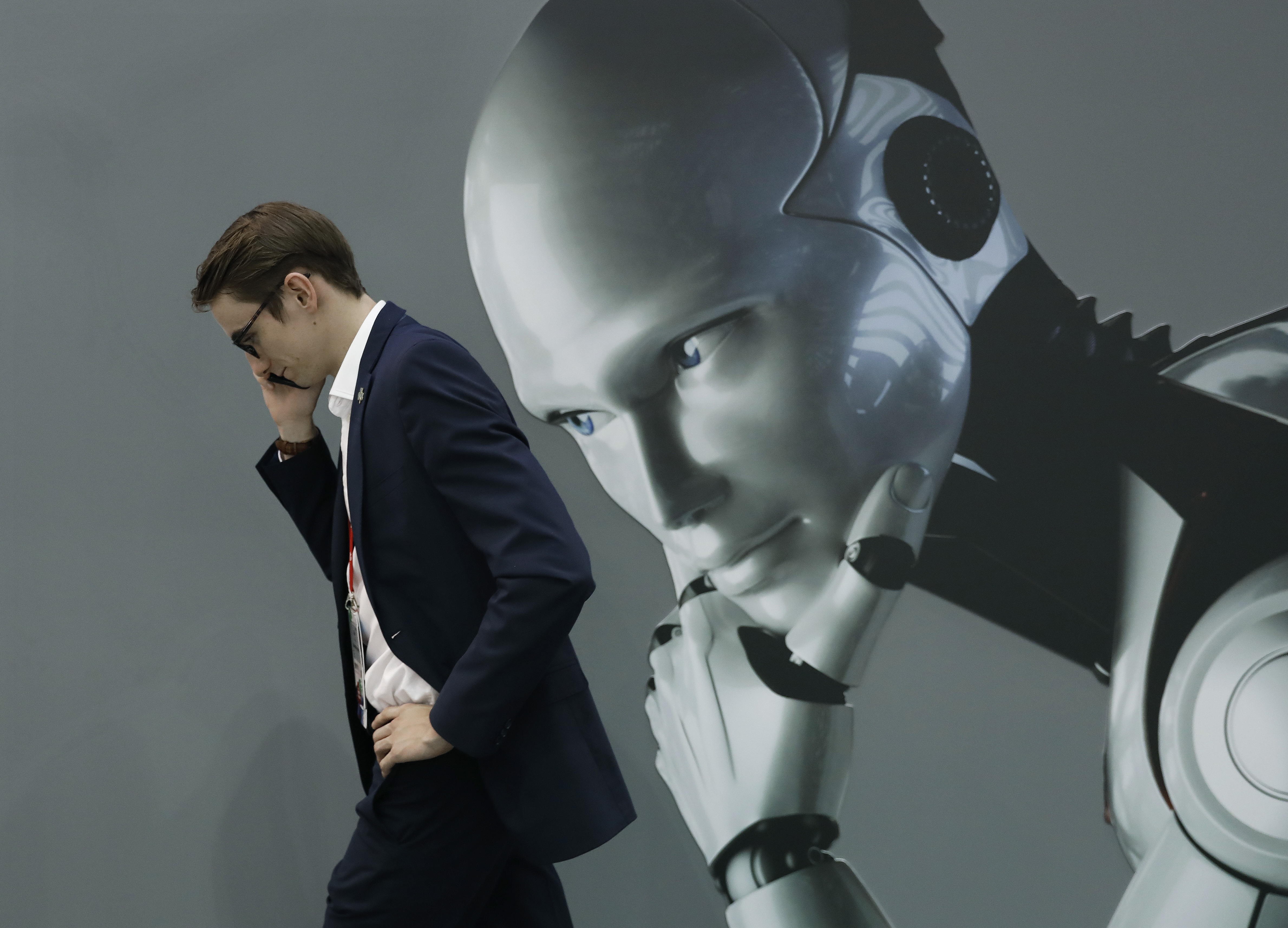BARCELONA, 29/12/2022.-Fotografía de archivo, tomada el 28/02/2018, de un visitante al Mobile World Congress (MWC) de Barcelona habla por teléfono mientras pasa por un estand de inteligencia artificial. La Fundación del Español Urgente (FundéuRAE), promovida por la Agencia EFE y la Real Academia Española, ha otorgado en 2022 el título de "palabra del año" a la expresión compleja "inteligencia artificial". Este jueves se ha comunicado su decisión ante una construcción incorporada al diccionario académico desde 1992 y definida como "disciplina científica que se ocupa de crear programas informáticos que ejecutan operaciones comparables a las que realiza la mente humana, como el aprendizaje o el razonamiento lógico". Según ha explicado FundéuRAE, los motivos de su elección han sido "su importante presencia en los medios de comunicación durante estos últimos doce meses, así como en el debate social, debido a los diversos avances desarrollados en este ámbito y las consecuencias éticas derivadas" como sería la posible sustitución de ciertos profesionales tras su aplicación en algunos ámbitos.EFE/Archivo/Andreu Dalmau