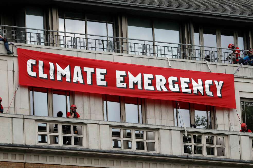 En las ventanas de la compañía, los activistas colgaron grandes letras que formaban las palabras "Emergencia climática". / AFP