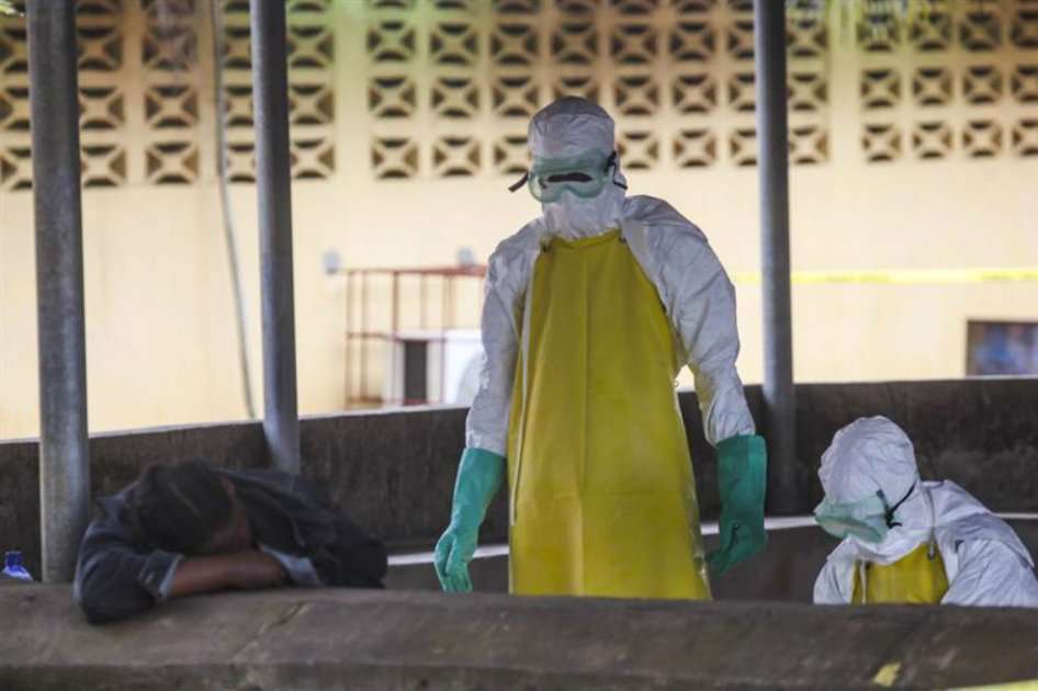 Trabajadores de salud liberianos se preparan para recoger el cuerpo de una víctima del ébola del área de espera de un hospital en Monrovia