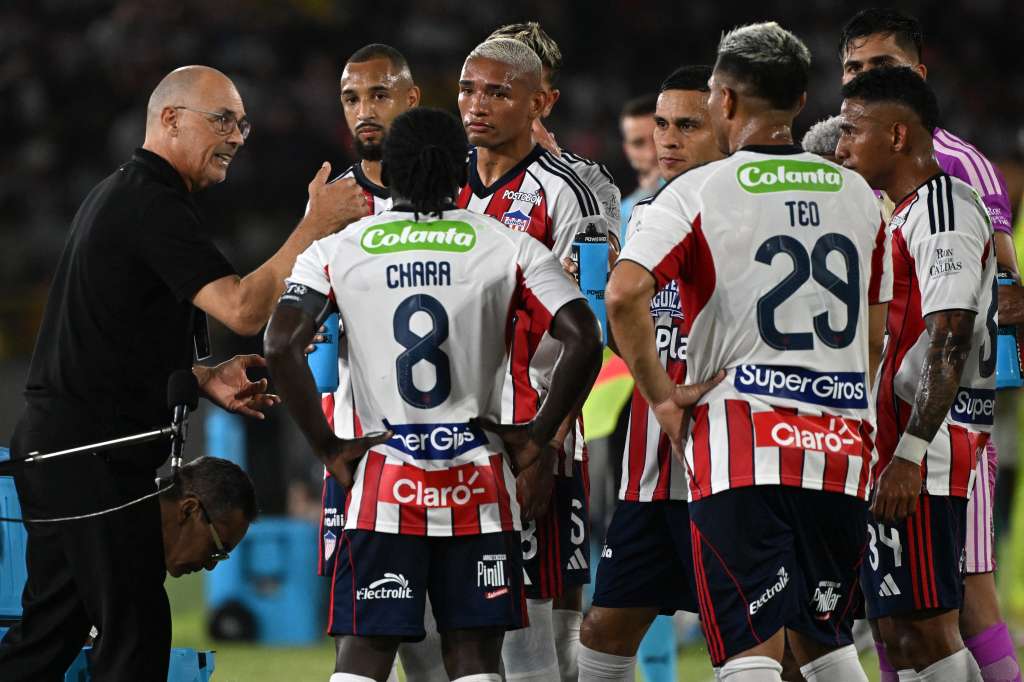 Junior's Uruguayan head coach Alfredo Arias speaks with his players during the Copa Libertadores group stage football match between Colombia's Junior and Brazil's Palmeiras at the Olimpico Jaime Moron Leon stadium in Cartagena, Bolivar department, Colombia, on April 8, 2026. (Photo by Luis ACOSTA / AFP)
