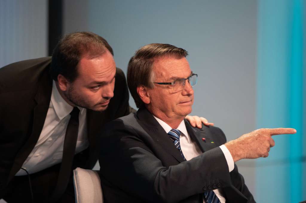 AME1001. RIO DE JANEIRO (BRASIL), 29/09/2022.- El presidente y candidato a reelección, Jair Bolsonaro (d), señala junto a su hijo Carlos durante un debate hoy, con los demás candidatos, en los estudios de TV Globo en Río de Janeiro (Brasil). Las elecciones para presidente en Brasil se llevarán a cabo el próximo domingo 2 de octubre y las encuestas recientes muestran a Lula y a Bolsonaro como los favoritos. EFE/André Coelho