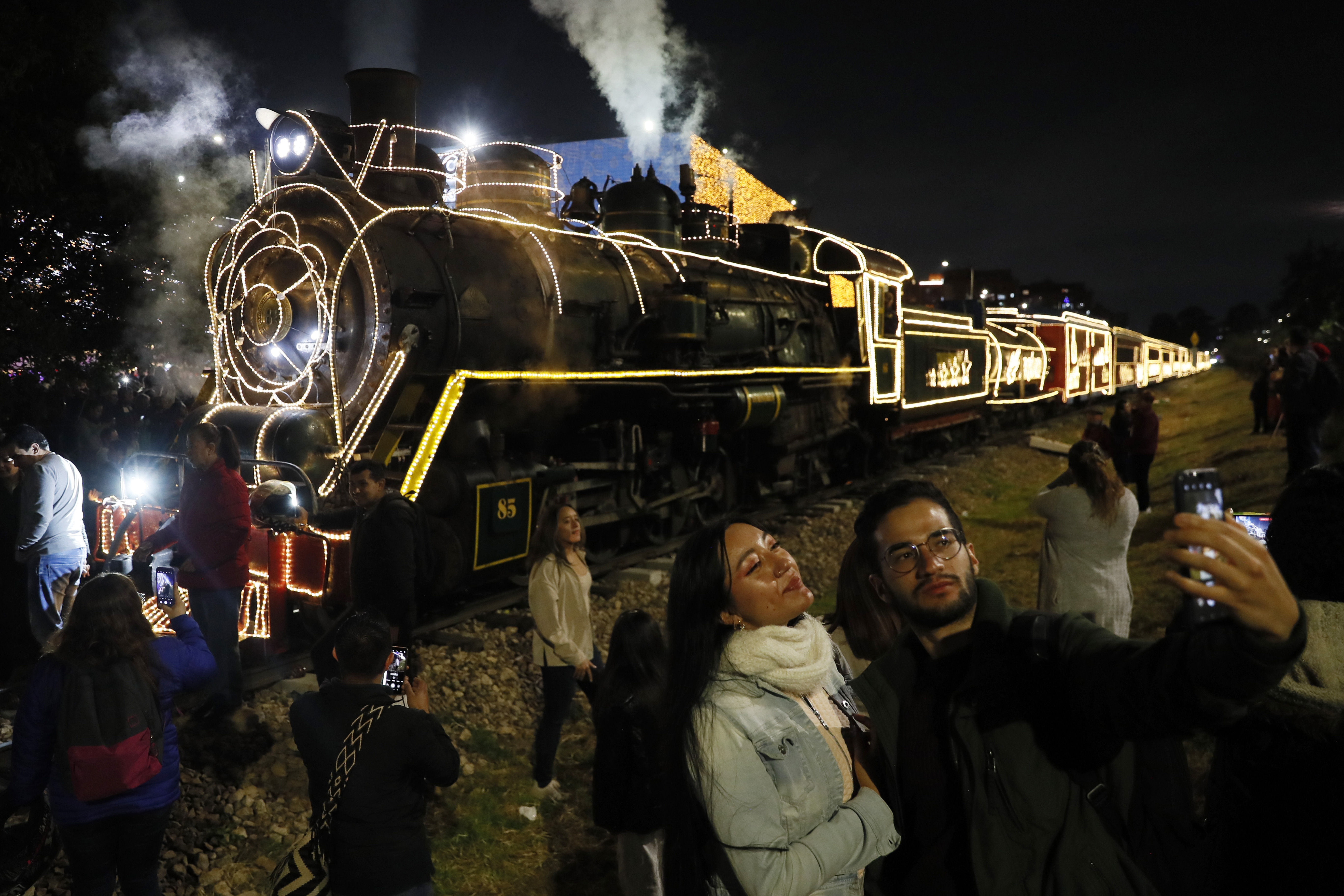 AME2768. BOGOTÁ (COLOMBIA), 07/12/2023.- Personas se toman fotos junto al Tren de la Sabana hoy, durante la tradicional noche de las velitas en Bogotá (Colombia). Los colombianos celebraron este jueves la tradicional noche de las velitas que marca el inicio de las conmemoraciones navideñas. EFE/Carlos Ortega