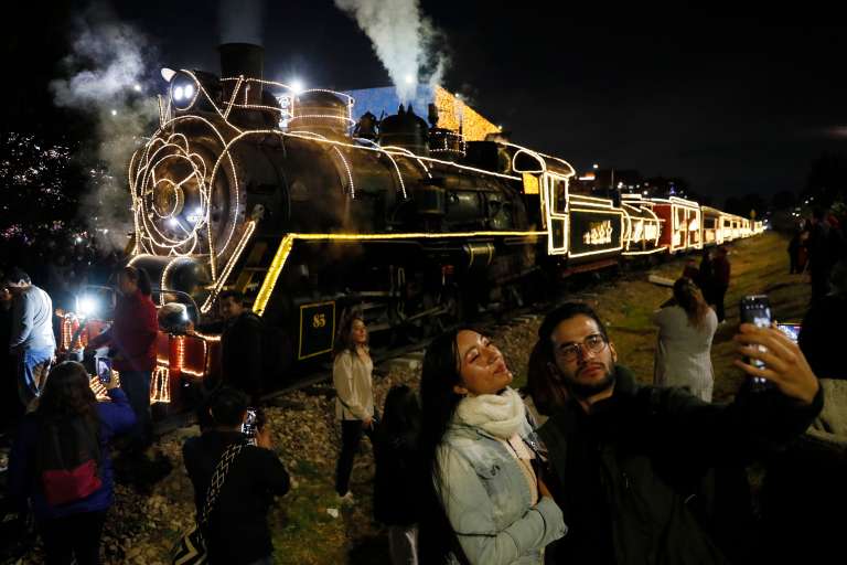 AME2768. BOGOTÁ (COLOMBIA), 07/12/2023.- Personas se toman fotos junto al Tren de la Sabana hoy, durante la tradicional noche de las velitas en Bogotá (Colombia). Los colombianos celebraron este jueves la tradicional noche de las velitas que marca el inicio de las conmemoraciones navideñas. EFE/Carlos Ortega