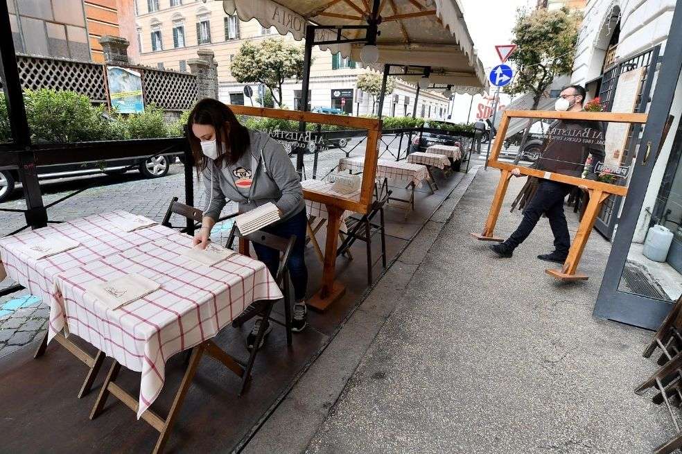 Miembros del personal de un restaurante organizan la reapertura de su negocio en Roma, Italia.