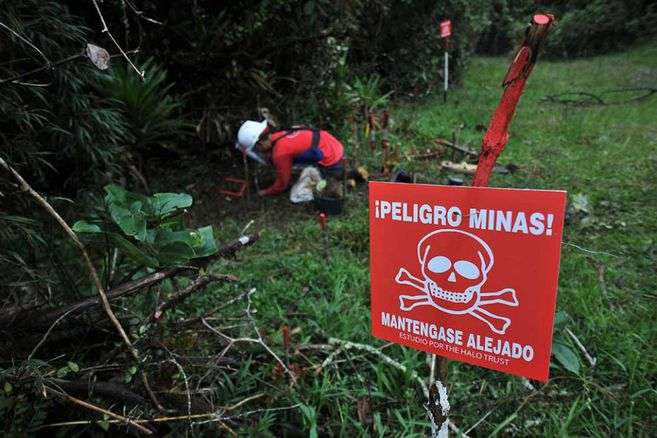 Un hombre está desinstalando una mina antipersonal.