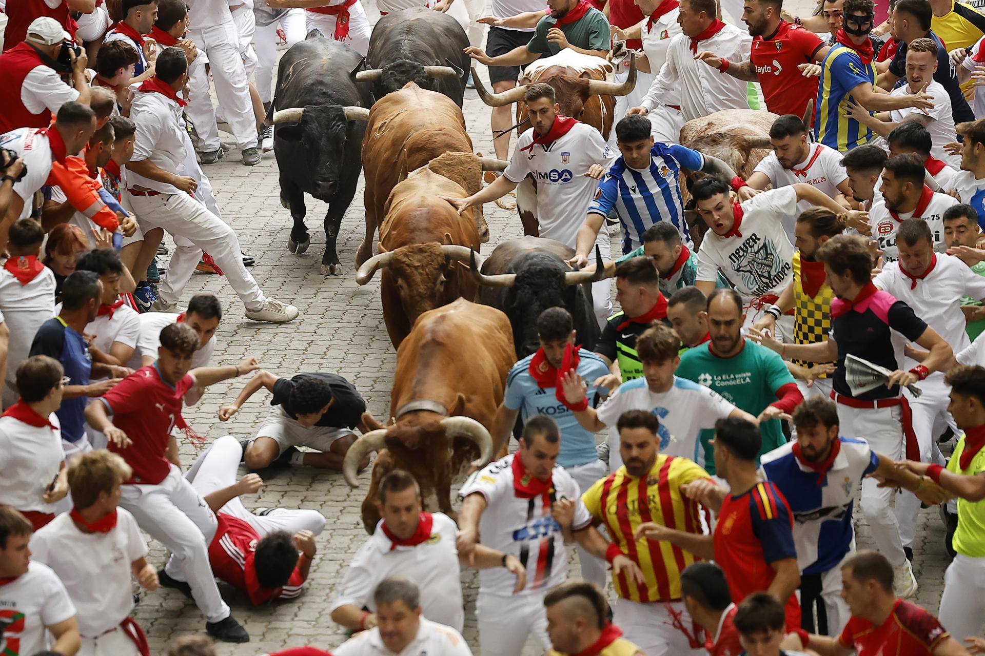 PAMPLONA, 10/07/2026.- Varios mozos caen ante los toros de la ganadería de Álvaro Núñez durante el cuarto encierro de los Sanfermines 2026 este viernes en Pamplona. EFE/Villar Lopez