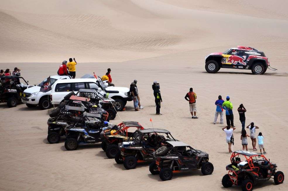 Los aficionados viajan varias horas para llegar al sitio en el que pueden ver pasar de cerca a los competidores del Rally Dakar en Perú. / AFP