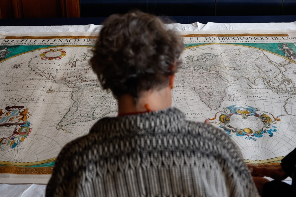 Paris (France), 01/04/2025.- A person inspects a 17th-century world map on display during a ceremony inside the Bibliotheque Nationale de France (BNF) in Paris, France, 01 April 2025. The map, printed in Paris around 1660, was seized in 2007 in Germany after being illegally removed from France. The French customs officially handed over the 17th-century world map and a gold penny minted during the reign of Charlemagne known as Solidus, of which only four copies exist, to the National Library in Paris. (Francia, Alemania) EFE/EPA/MOHAMMED BADRA
