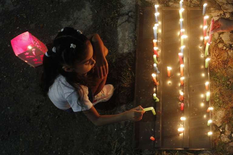 MED108 -MEDELLÍN(COLOMBIA), 07/12/2023. Una niña enciende una vela durante la tradicional noche de las velitas hoy, en Medellín (Colombia). Esta costumbre colombiana celebra el día de la Inmaculada Concepción y marca el inicio de las conmemoraciones navideñas. EFE/Luis Eduardo Noriega Arboleda
