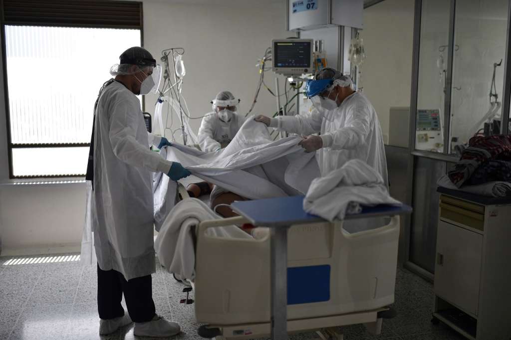 Tres personas moviendo a un paciente en una cama
