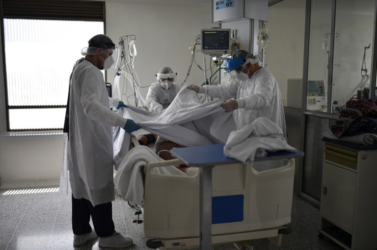 Tres personas moviendo a un paciente en una cama