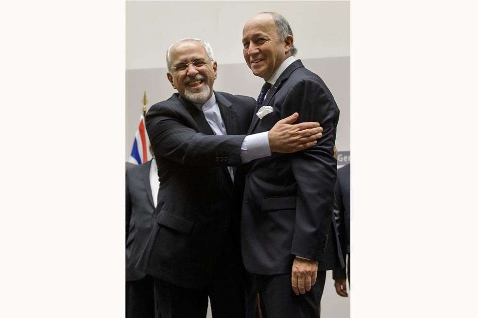 El canciller iraní, Mohamad Javad Zarif, saluda al canciller francés, Laurent Fabius, después del anuncio del acuerdo alcanzado en Ginebra. / AFP