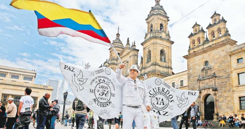 Un hombre ondea la bandera de Colombia junto a cientos de personas que se congregaron en la Plaza de Bolívar para observar la firma del nuevo acuerdo de paz el jueVes 24 de noviembre de 2016. EFE/LEONARDO MUÑOOZ