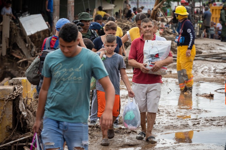 AME3286. TEJERIAS (VENEZUELA), 09/10/2022.- Personas cargan con algunas pertenencias tras las perdidas que sufrieron con las lluvias y desbordamiento de la quebrada (rio) Los Patos en Las Tejerias, estado Aragua (Venezuela). La crecida de una quebrada este sábado arrastró viviendas, mobiliario urbano, e inundó las calles de la localidad, arrasando con todo lo que el agua encontró a su paso. El Gobierno desplegó hoy organismos de salvamento, seguridad ciudadana, así como cuadrillas de mantenimiento y limpieza, y personal de diversas instituciones para "la atención integral del pueblo", dijo el presidente Nicolás Maduro a través de su cuenta de Twitter.EFE/ Rayner Peña R.