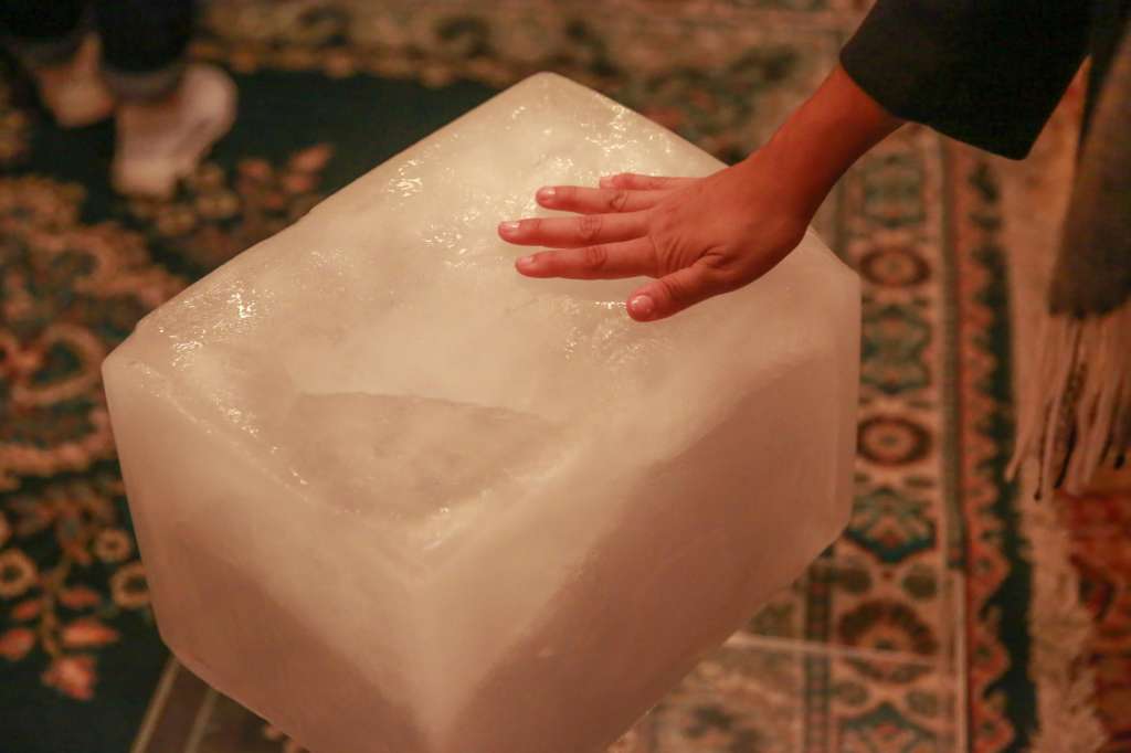 Una persona toca un bloque de hielo dispuesto en el hall del Teatro Solís, el 4 de octubre de 2023 en Montevideo (Uruguay).