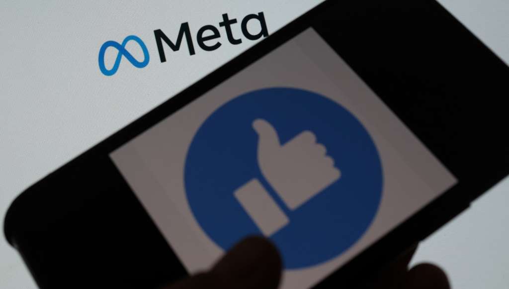 (FILES) A file photo taken on October 28, 2021 and taken in Los Angeles shows a person using Facebook on a smartphone in front of a computer screen showing the META logo. - Facebook launches in France from February 15, 2022, its news feed reserved for journalistic content, Facebook News, it was announced by the American group Meta, owner of the social network on February 14, 2022. (Photo by Chris DELMAS / AFP)