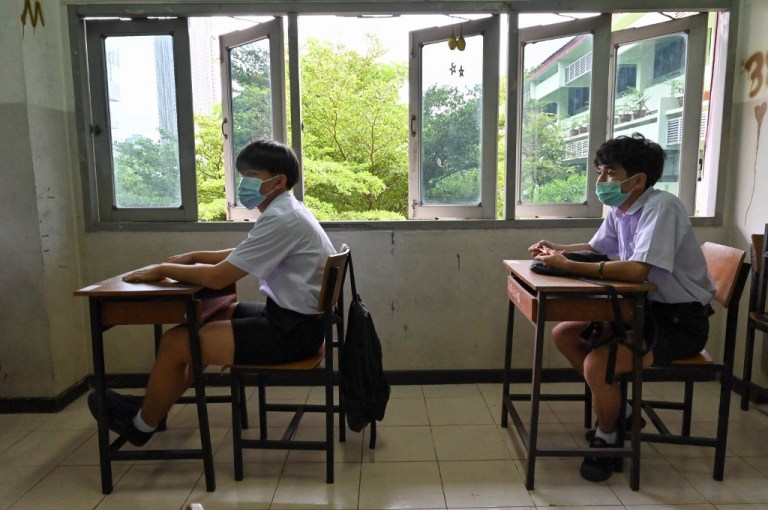 Dos estudiantes conservan el distanciamiento social en un aula de la escuela secundaria pública de Makkasan Phitthaya en Bangkok