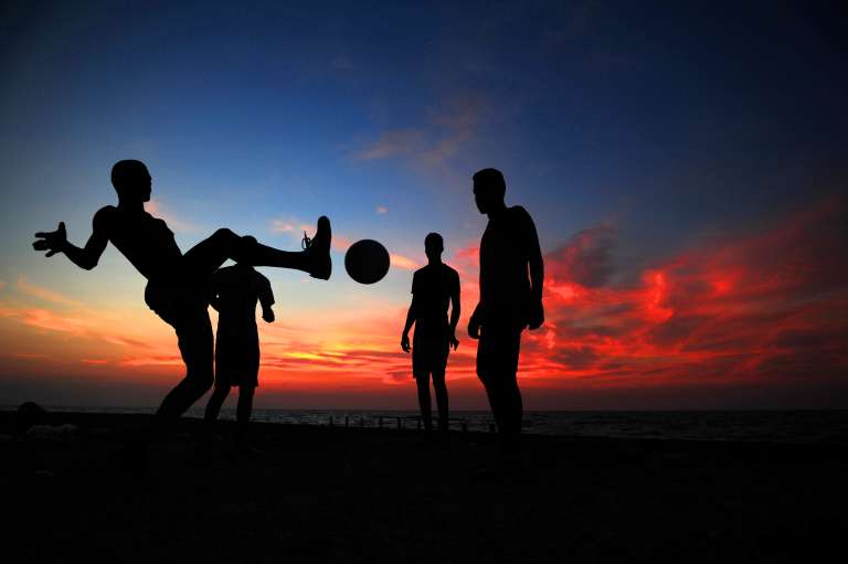 Jóvenes juegan fútbol en una playa de Cartagena.