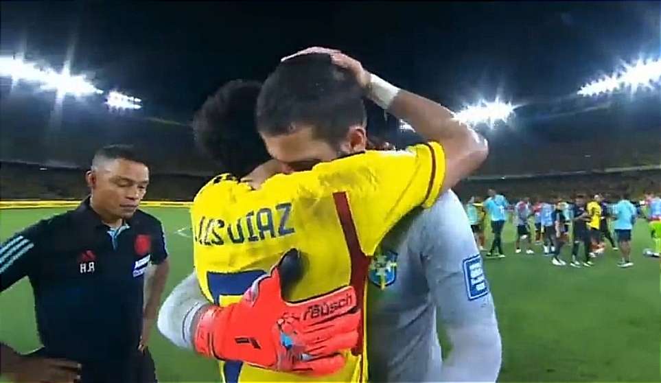 Luis Díaz, de Colombia, y Allison Becker, de Brasil, compañeros de Liverpool de Inglaterra comparten un abrazo tras su choque en Eliminatorias.