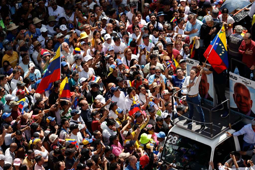 AME1189. CARACAS (VENEZUELA), 17/08/2024.- La líder de la oposición venezolana María Corina Machado (d) agita la bandera de Venezuela frente a seguidores este sábado, en Caracas (Venezuela). Machado reapareció en público para participar en la concentración contra el resultado oficial de las presidenciales que -asegura- ganó el abanderado de la mayor coalición opositora, Edmundo González Urrutia, pese a que el Consejo Nacional Electoral (CNE) otorgó el triunfo a Nicolás Maduro. EFE/ Miguel Gutiérrez