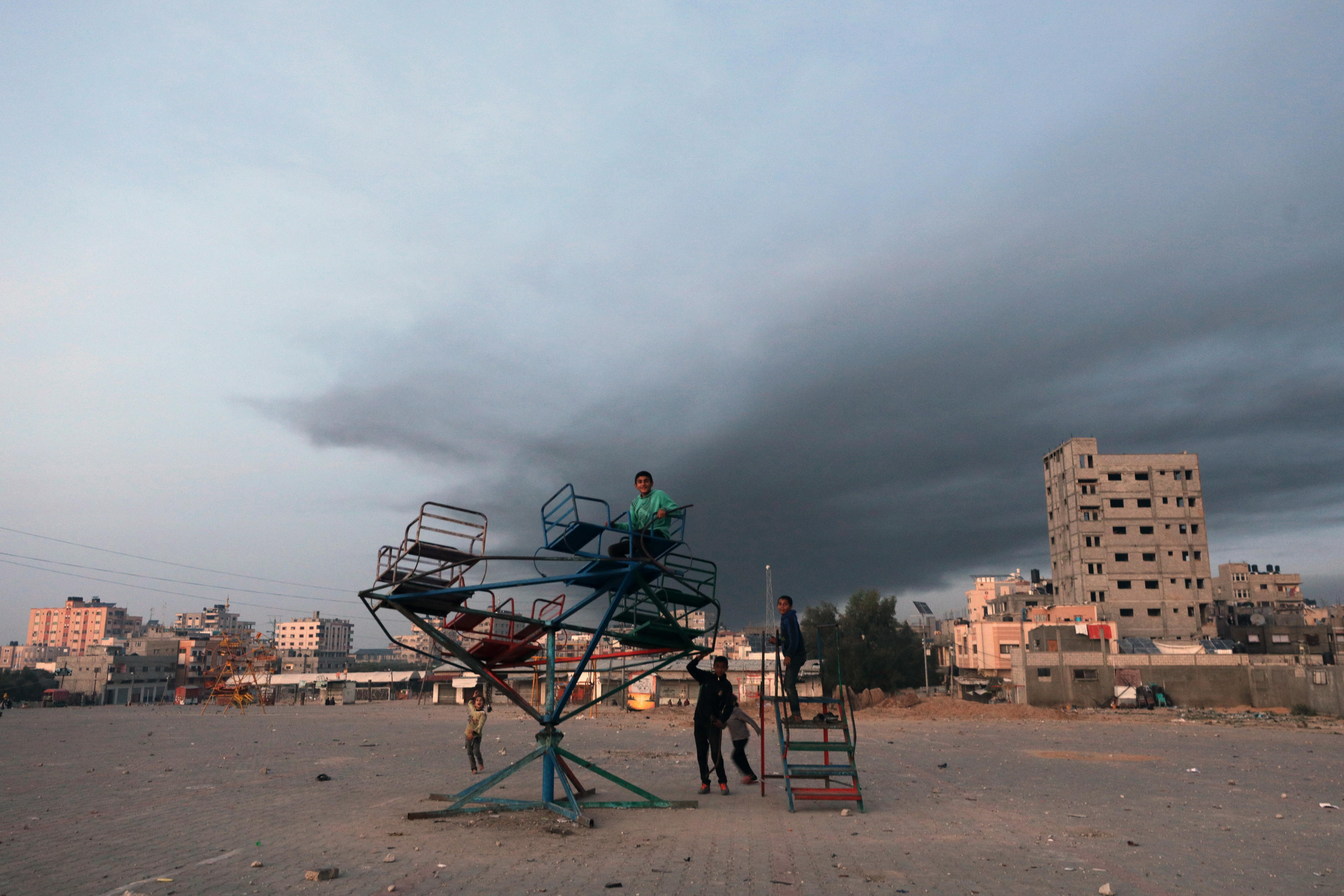 -FOTODELDÍA- SUR DE LA FRANJA DE GAZA, 03/12/2023.- Niños juegan cerca de una columna de humo provocada por ataques aéreos israelíes, este domingo en el sur de la Franja de Gaza, después del fin de la tregua de una semana que Hamas e Israel pactaron recientemente. EFE/MOHAMMED SABER
