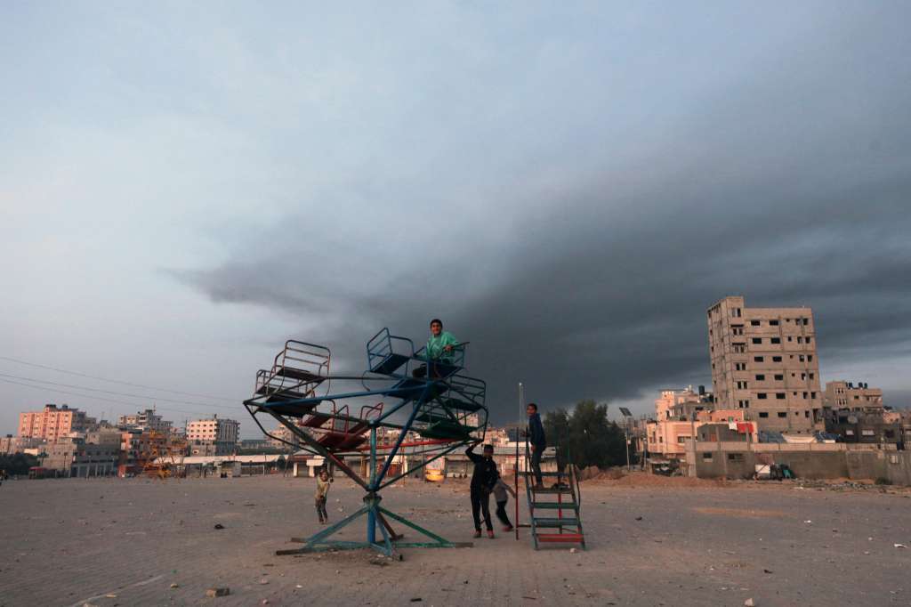 -FOTODELDÍA- SUR DE LA FRANJA DE GAZA, 03/12/2023.- Niños juegan cerca de una columna de humo provocada por ataques aéreos israelíes, este domingo en el sur de la Franja de Gaza, después del fin de la tregua de una semana que Hamas e Israel pactaron recientemente. EFE/MOHAMMED SABER